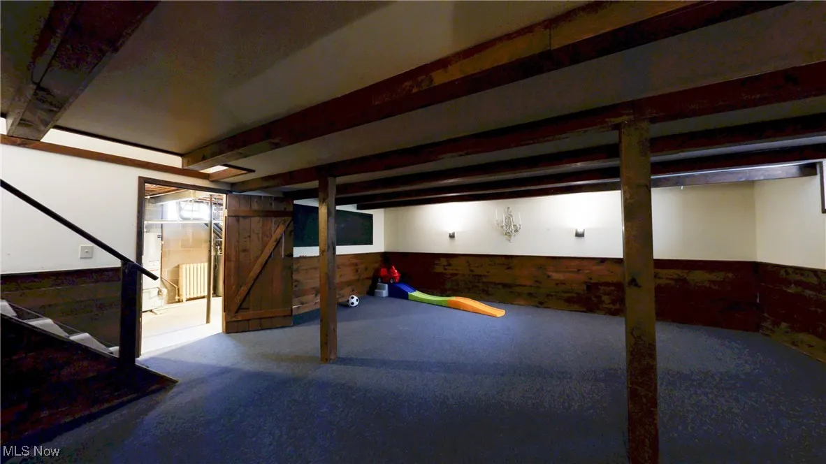 Finished below grade area featuring stairway, wooden walls, and wainscoting