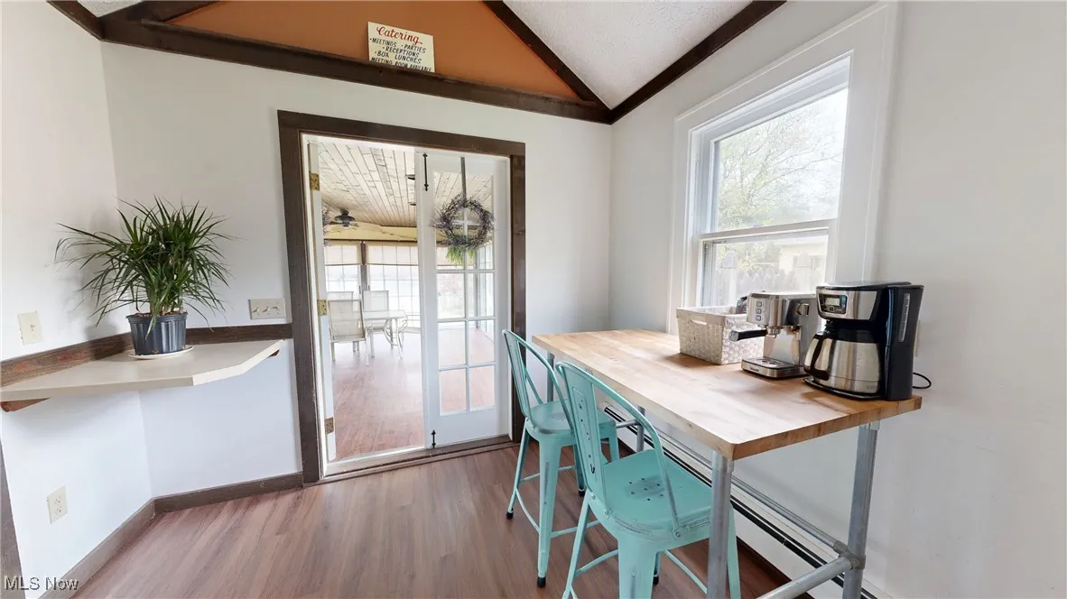 Dining area with baseboards, wood finished floors, a wealth of natural light, and vaulted ceiling
