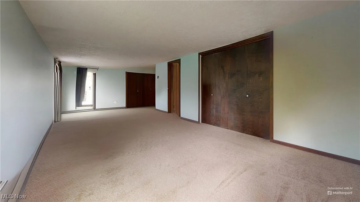 Carpeted empty room with baseboards and a textured ceiling