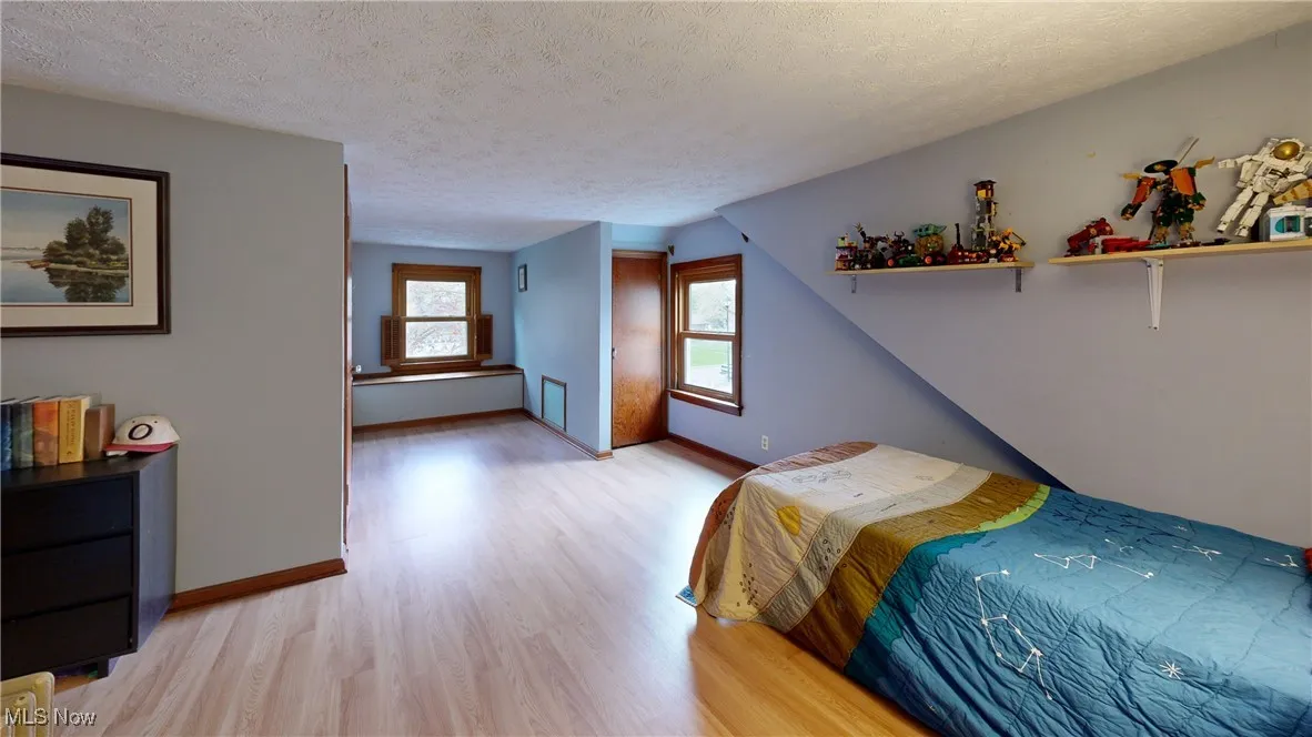 Bedroom featuring a textured ceiling, light wood-style flooring, and baseboards