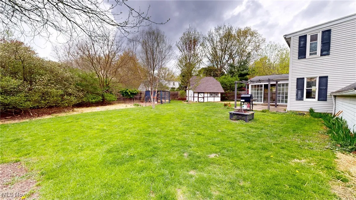 View of yard featuring an outbuilding, a storage unit, a fire pit, and fence