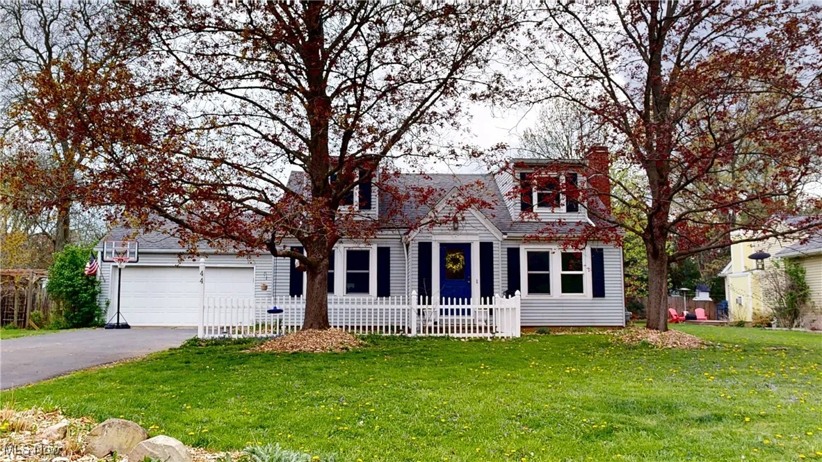 View of front of home with aphalt driveway, a chimney, fence, a front lawn, and a garage