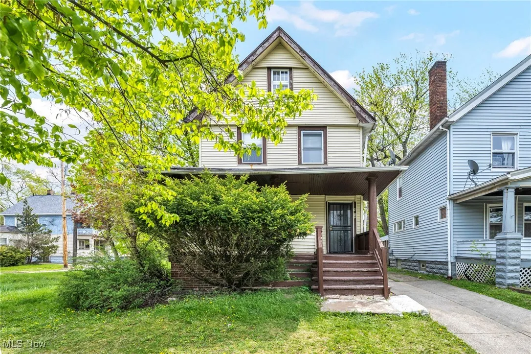American foursquare style home featuring a porch and a front lawn