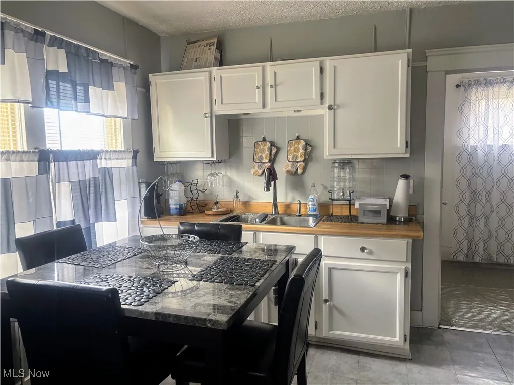 Kitchen featuring healthy amount of natural light, white cabinets, and wooden counters