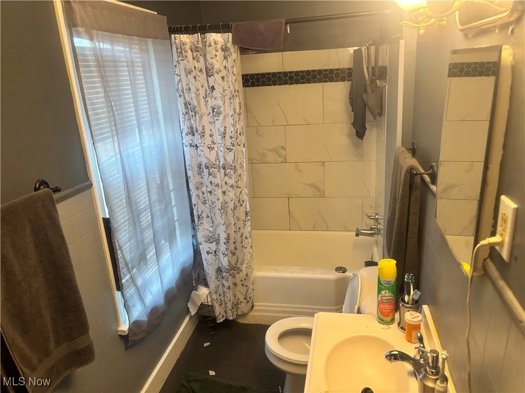 Full bathroom with shower / bath combo with shower curtain and tile patterned flooring