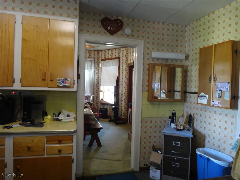 Kitchen featuring wallpapered walls. Lots of cabinetry for storage