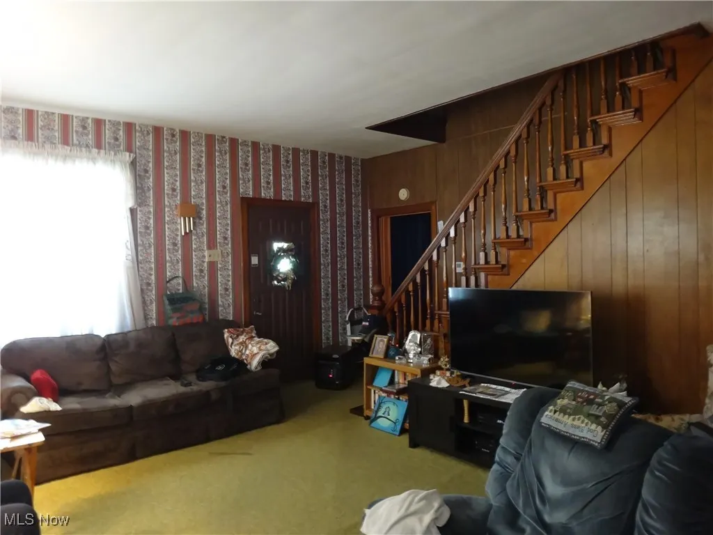 Living room featuring stairs, wallpapered walls, and carpet floors