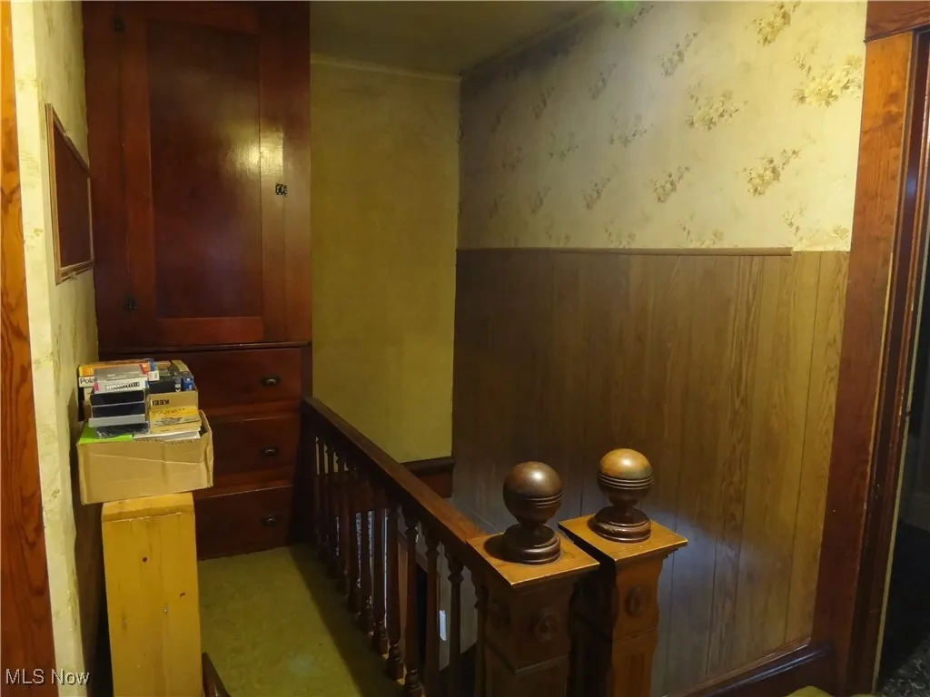 Corridor featuring a wainscoted wall and wallpapered walls