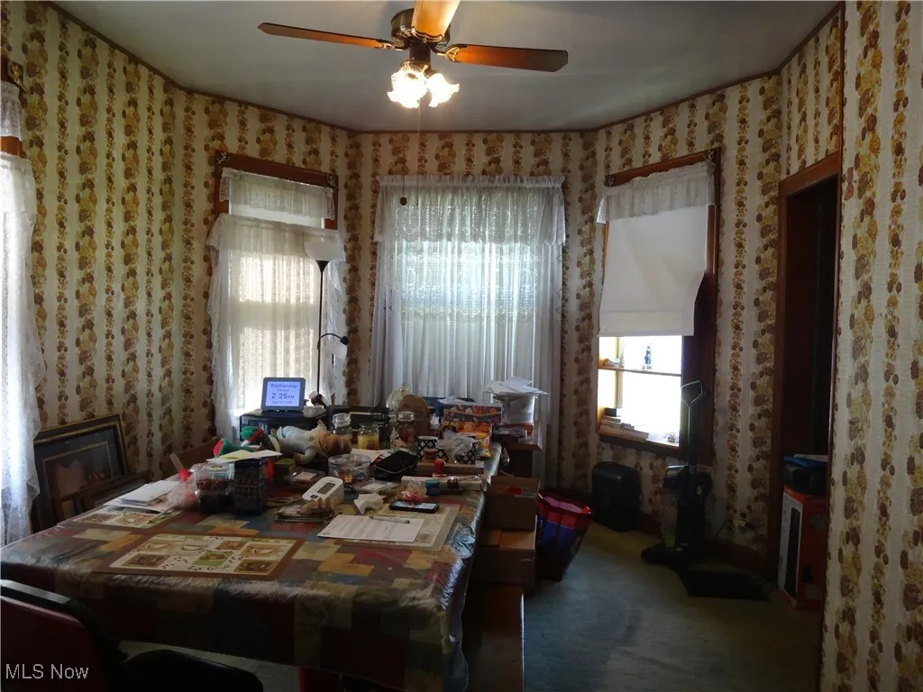 Dining area with a ceiling fan, carpet, a wealth of natural light, and wallpapered walls