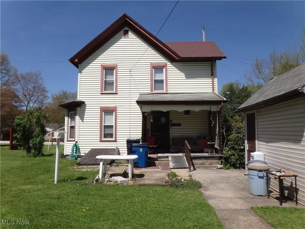 Rear view of house featuring a shingled roof, a yard, and a porch