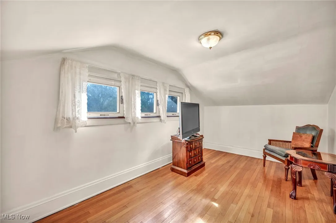Additional living space featuring baseboards, light wood-style flooring, and vaulted ceiling