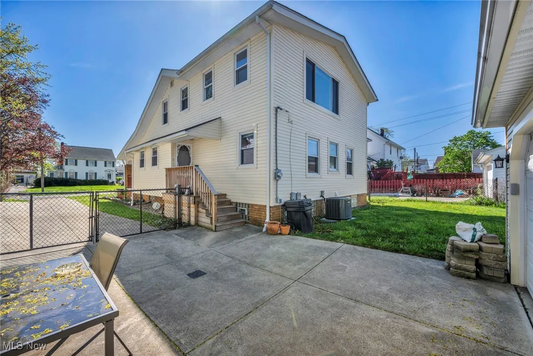 Rear view of property featuring a gate, a patio area, central AC, fence, and a yard