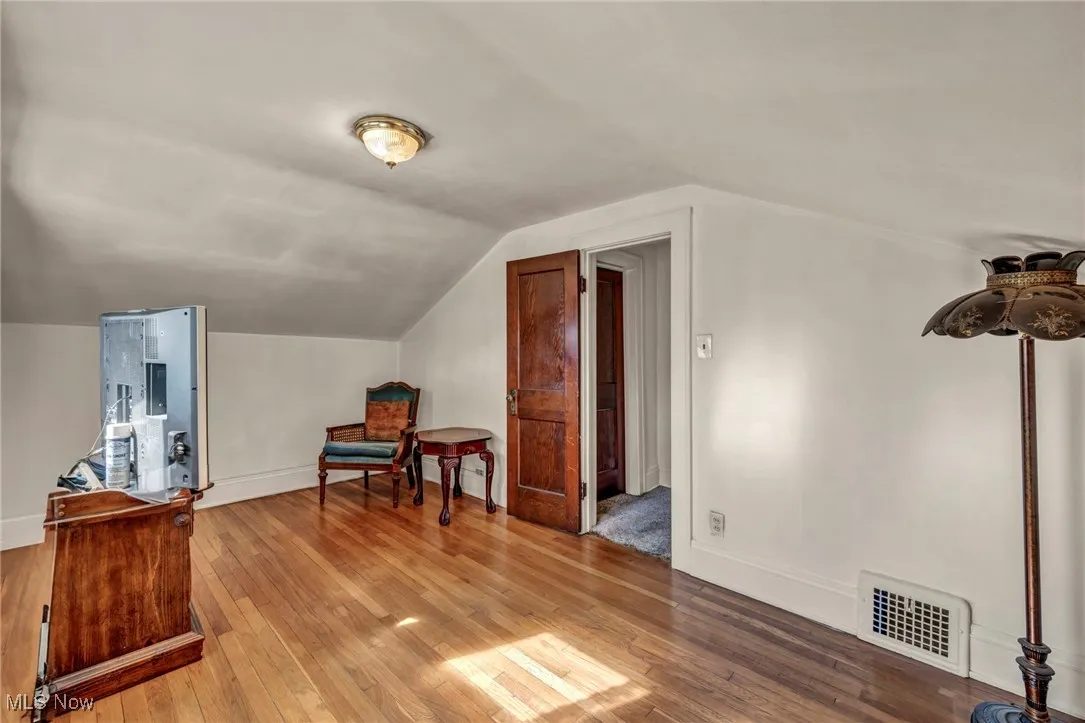 Additional living space featuring baseboards, wood-type flooring, lofted ceiling, and visible vents