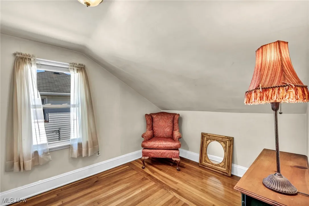 Living area featuring baseboards, wood finished floors, and lofted ceiling