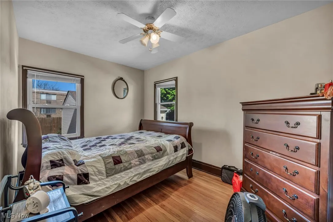 Bedroom with a textured ceiling, baseboards, a ceiling fan, and light wood finished floors
