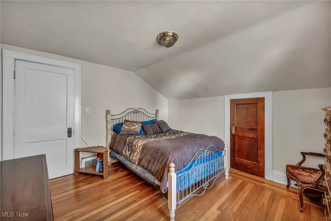Bedroom featuring wood-type flooring, baseboards, and lofted​​‌​​​​‌​​‌‌​‌‌​​​‌‌​‌​‌​‌​​​‌​​ ceiling