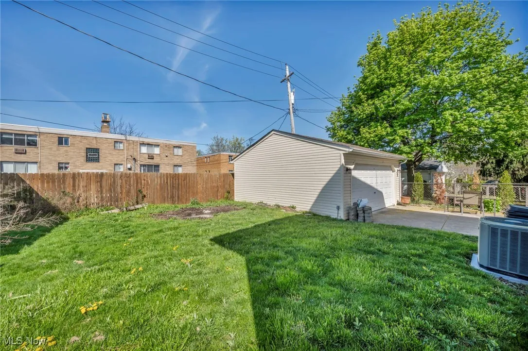 View of yard featuring an outdoor structure, fence, central air condition unit, and a detached garage
