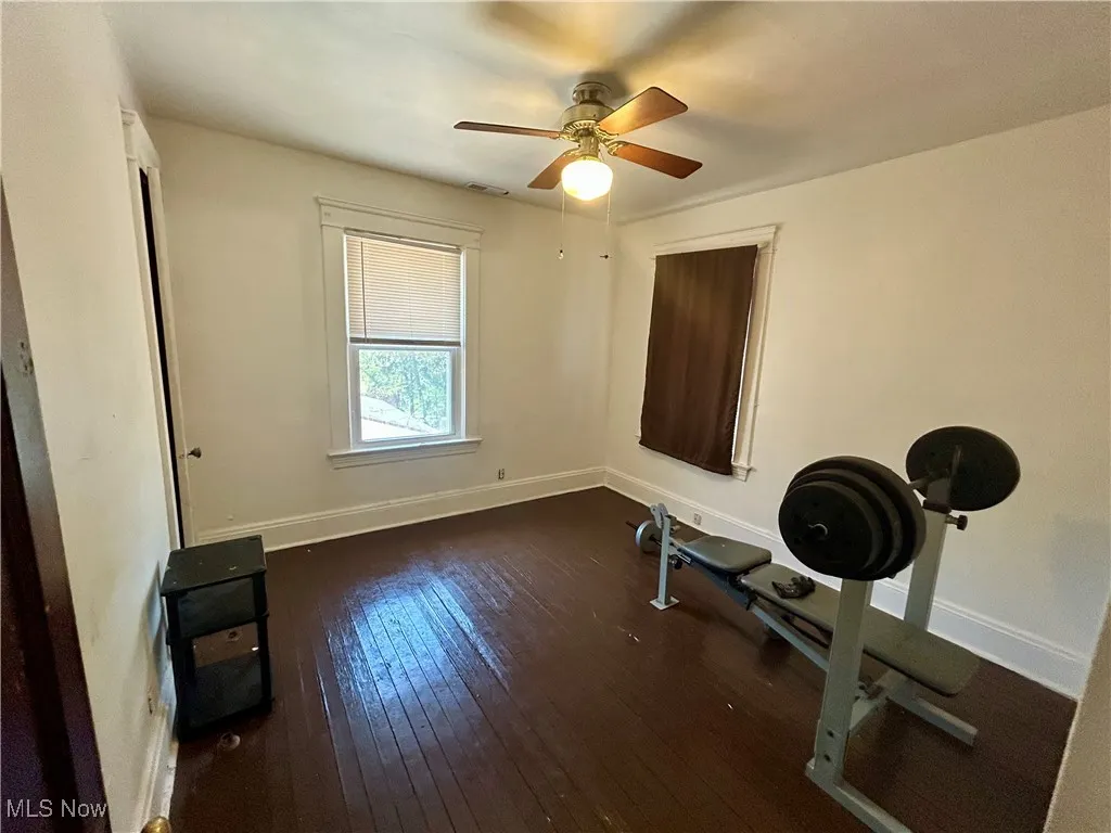 Workout area featuring wood-type flooring, a ceiling fan, baseboards, and visible vents