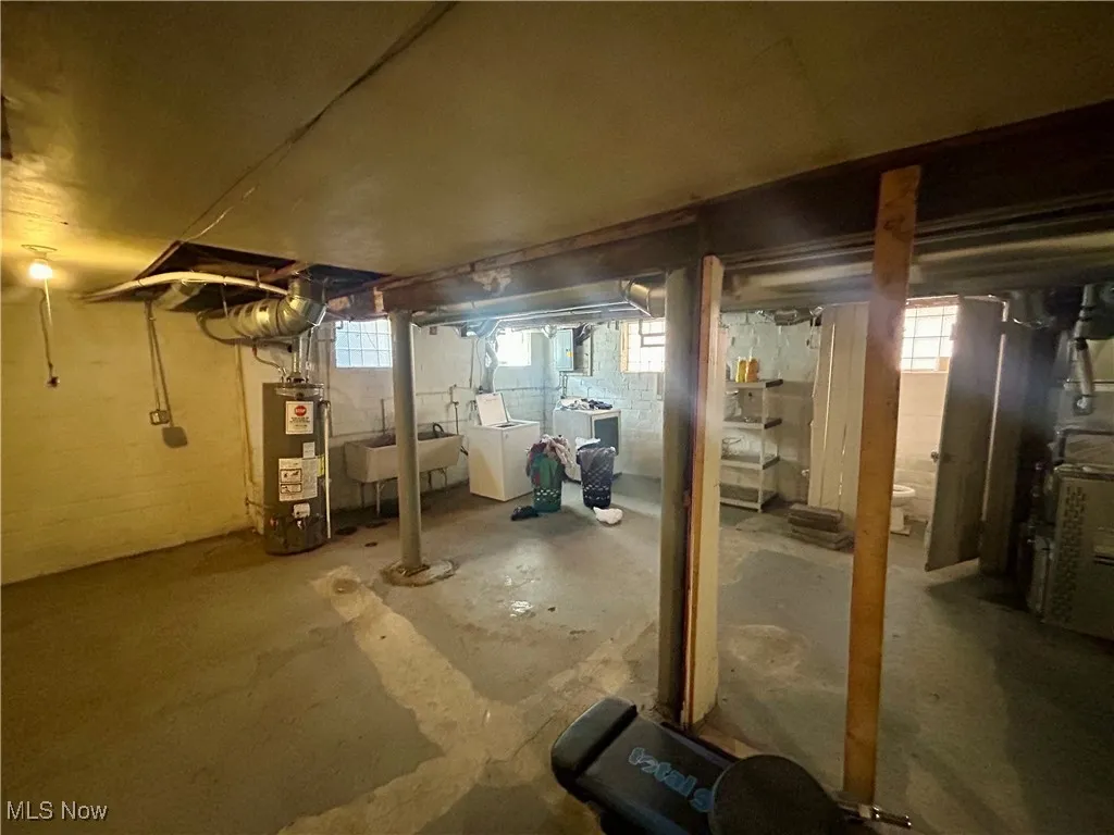 Basement with water heater, a sink, and washing machine and clothes dryer