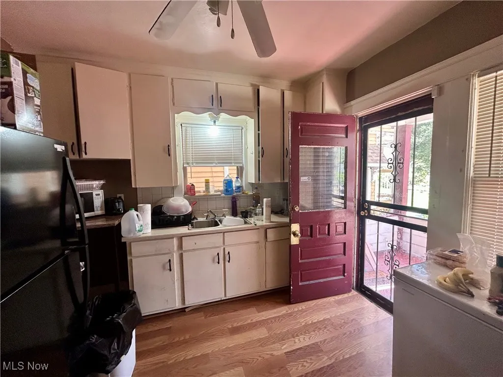 Kitchen with freestanding refrigerator, white cabinets, light wood-style flooring, and light countertops