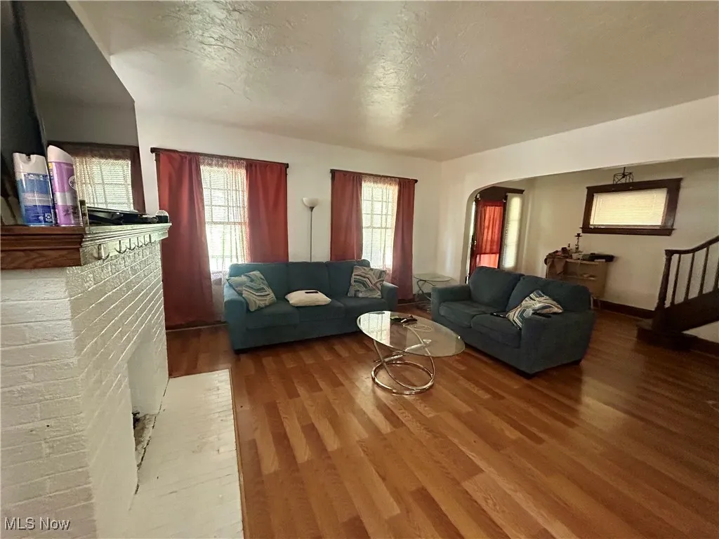Living room featuring arched walkways, a textured ceiling, and wood finished floors