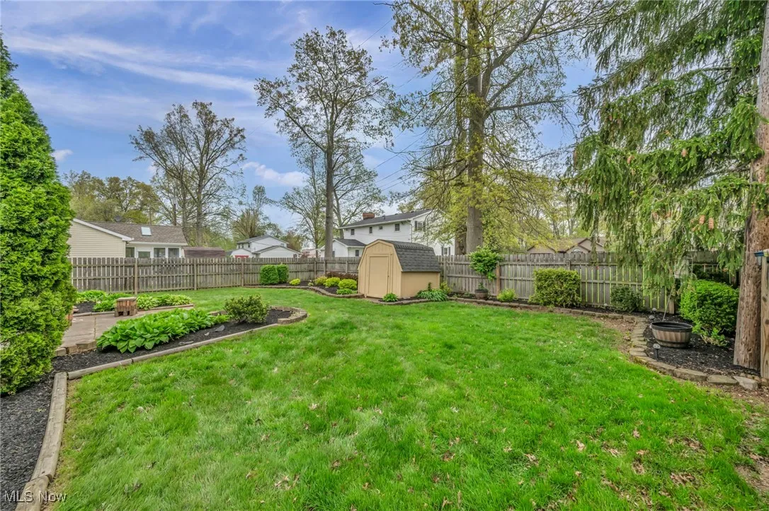 View of yard featuring a storage shed, an outdoor structure, and a fenced backyard