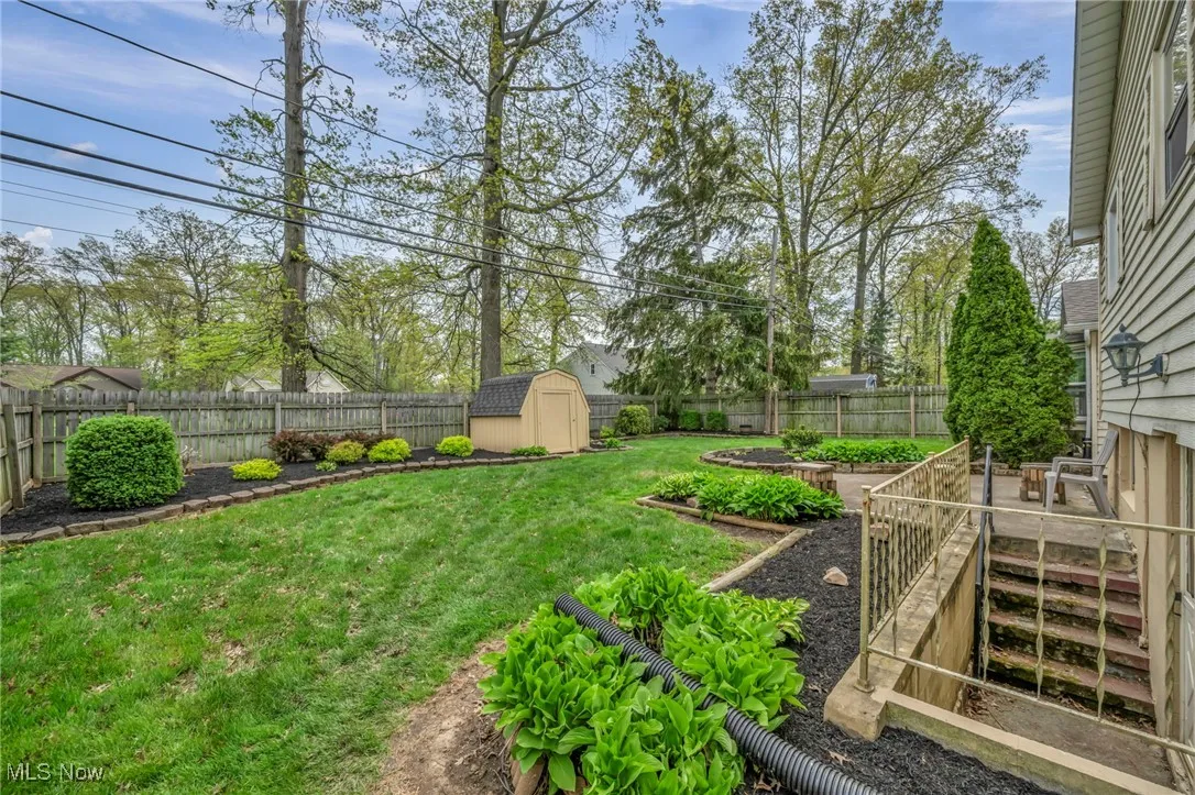 View of yard featuring a storage unit, a fenced backyard, a garden, and an outbuilding