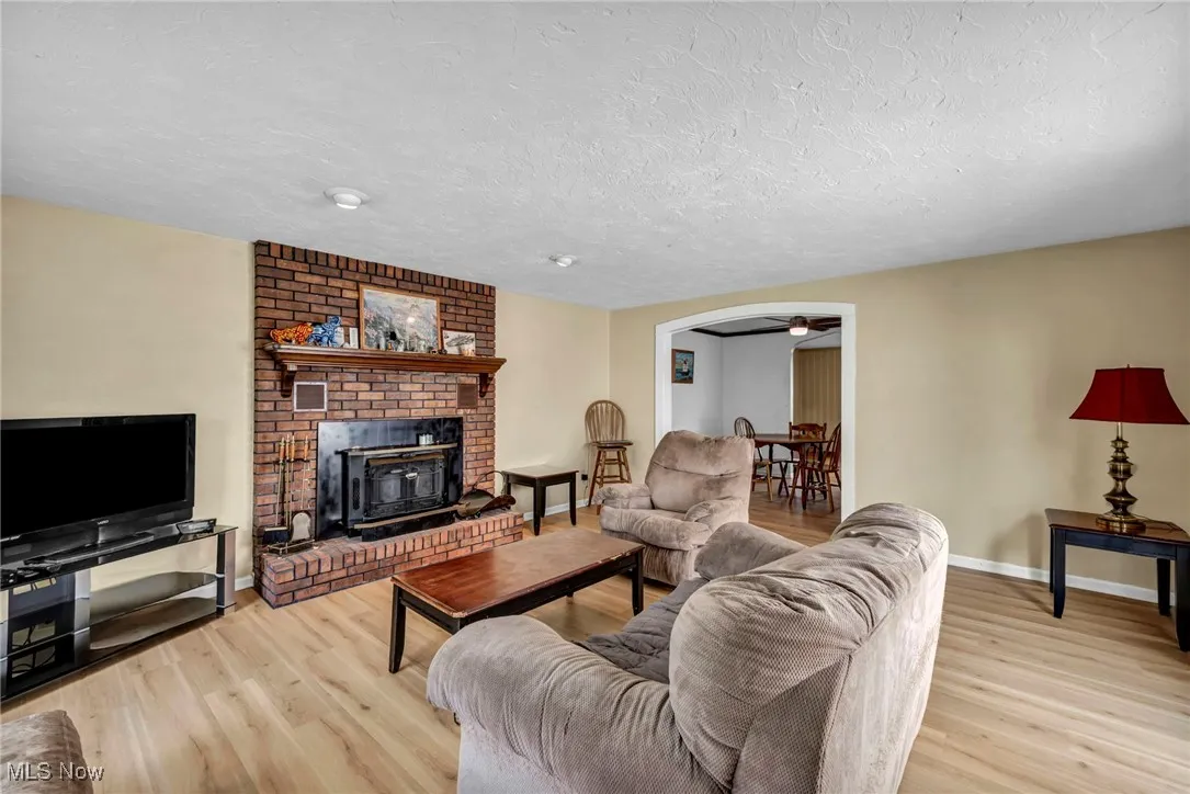 Living room featuring arched walkways, baseboards, a textured ceiling, and wood finished floors