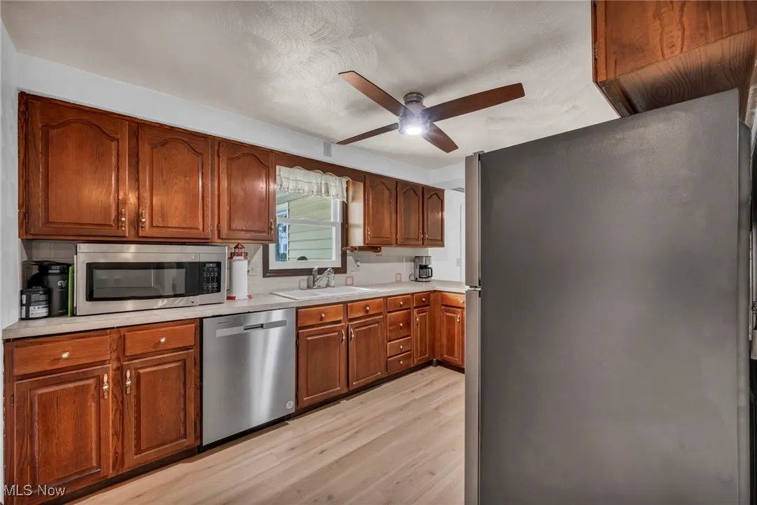 Kitchen with a sink, light countertops, a ceiling fan, light wood finished floors, and appliances with stainless steel​​‌​​​​‌​​‌‌​‌‌​​​‌‌​‌​‌​‌​​​‌​​ finishes