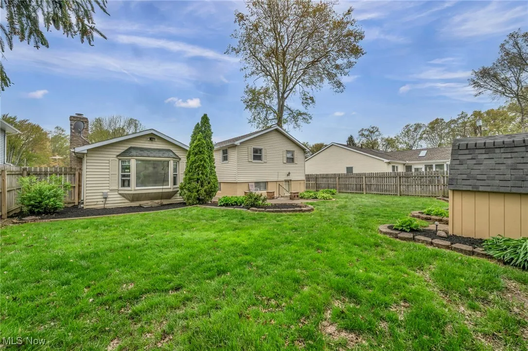 Back of house featuring a lawn, a fenced backyard, a shed, and an outbuilding