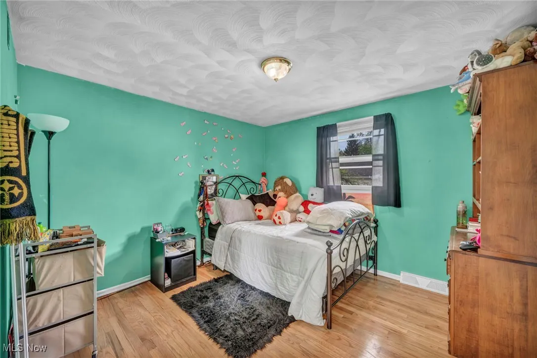 Bedroom with baseboards, visible vents, and wood finished floors