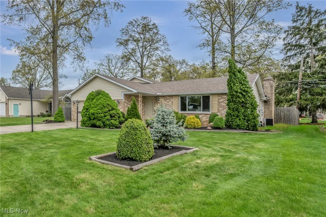 Ranch-style home featuring brick siding, a garage, a front yard, central AC unit, and concrete driveway