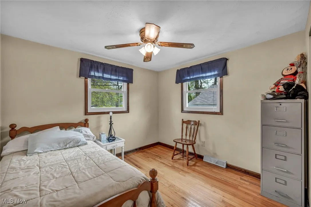 Bedroom featuring baseboards, visible vents, multiple windows, and light wood finished floors