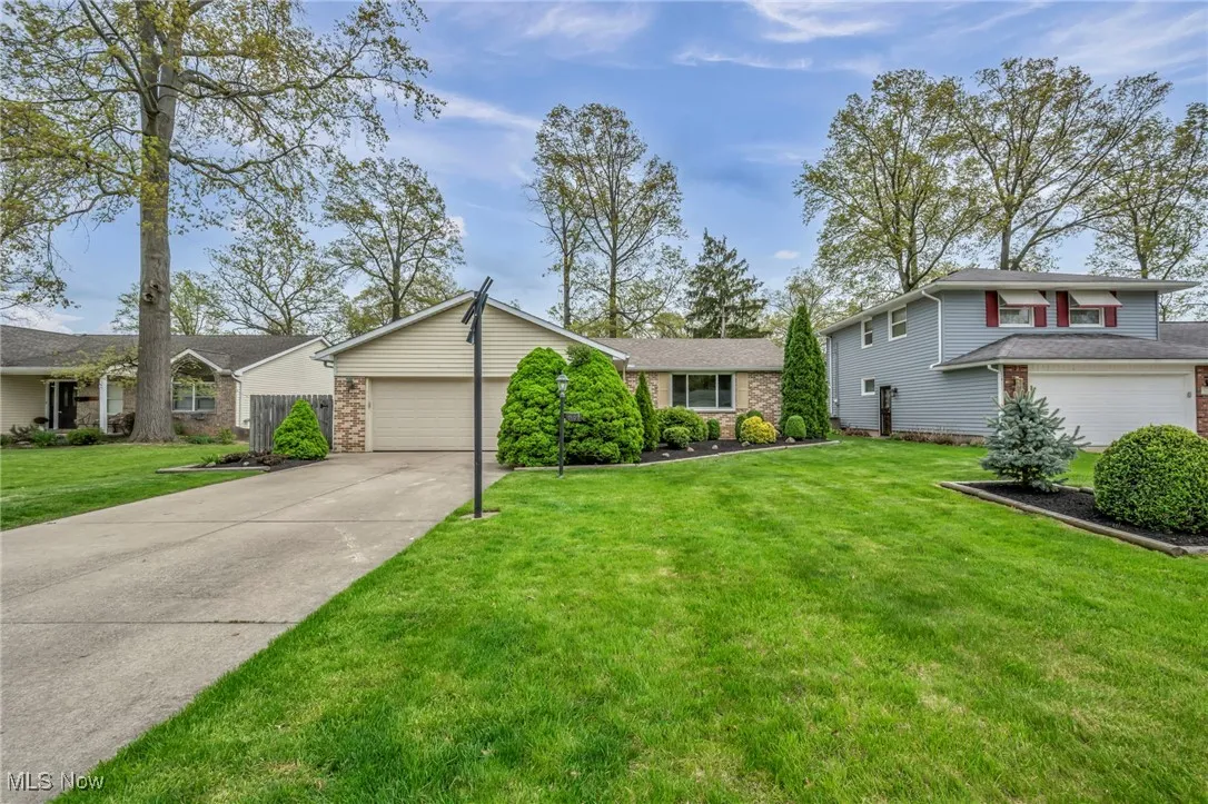 View of front of home featuring an attached garage, a front yard, brick siding, and concrete driveway