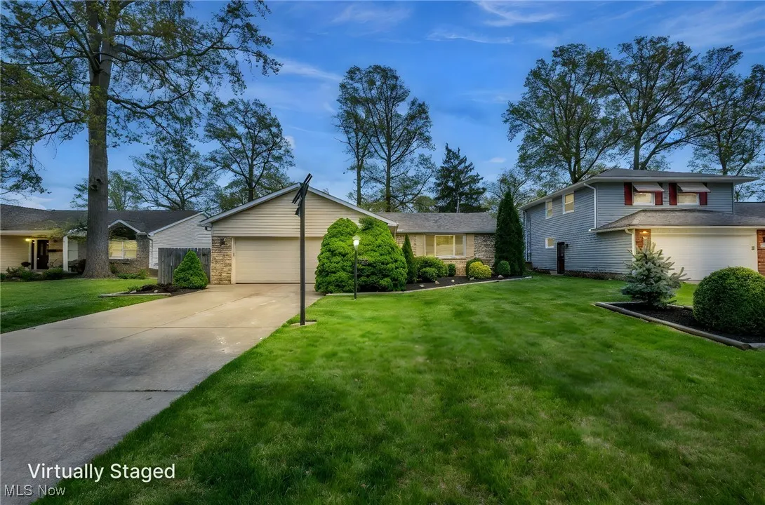 View of front of house with an attached garage, brick siding, driveway, and a front yard