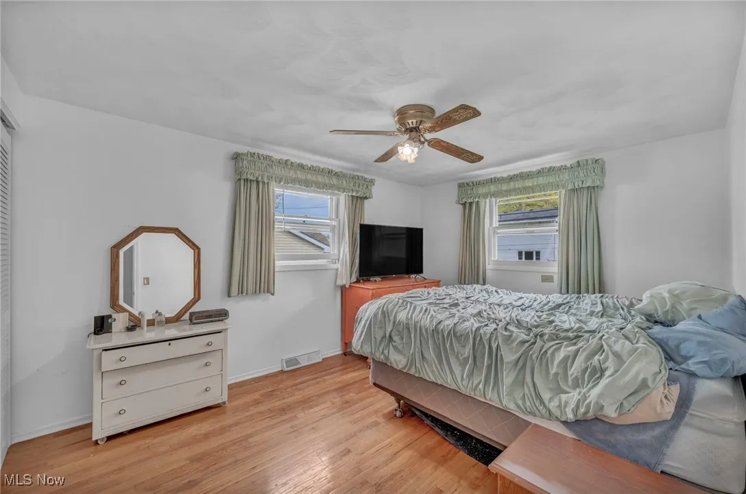 Bedroom featuring baseboards, multiple windows, light wood-style flooring, and visible vents