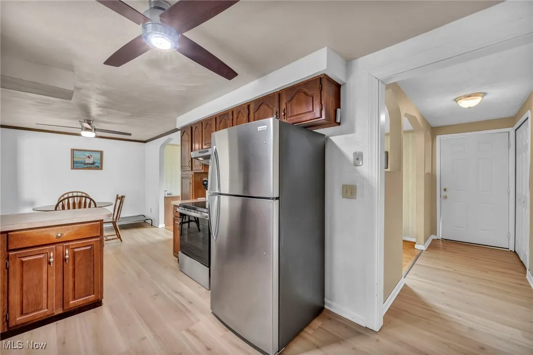 Kitchen featuring under cabinet range hood, ceiling fan, appliances with stainless steel finishes, and baseboards