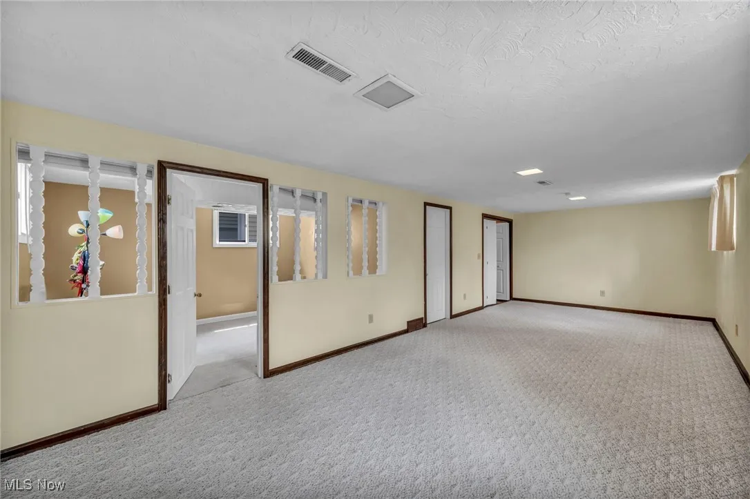 Carpeted spare room featuring baseboards and visible vents