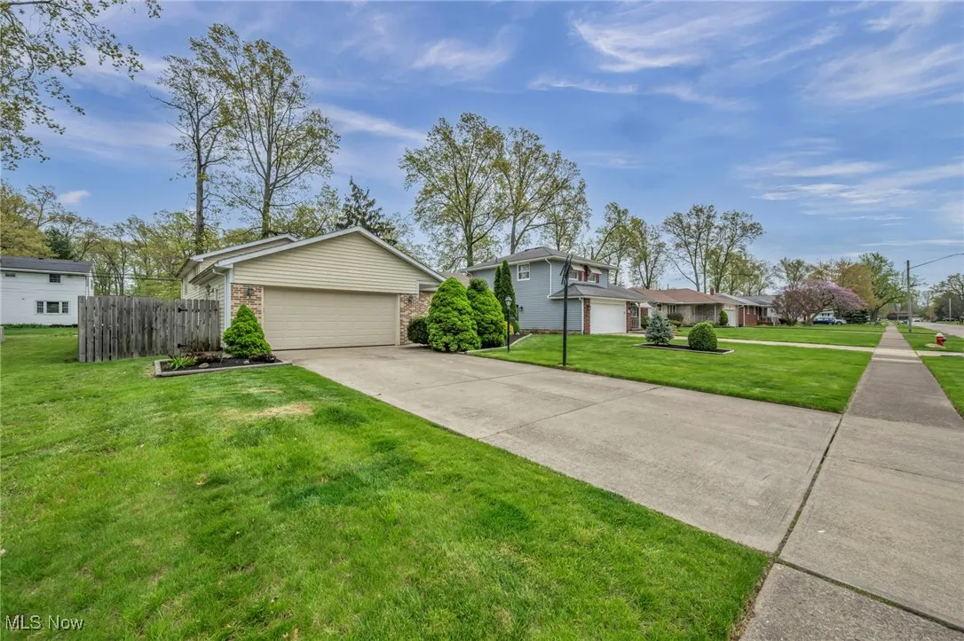 View of front of house with fence, a front lawn, brick siding, a garage, and driveway