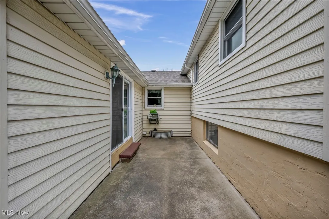 View of side of property with a patio and roof with shingles