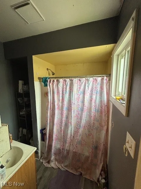 Bathroom featuring visible vents, vanity, curtained shower, and wood finished floors