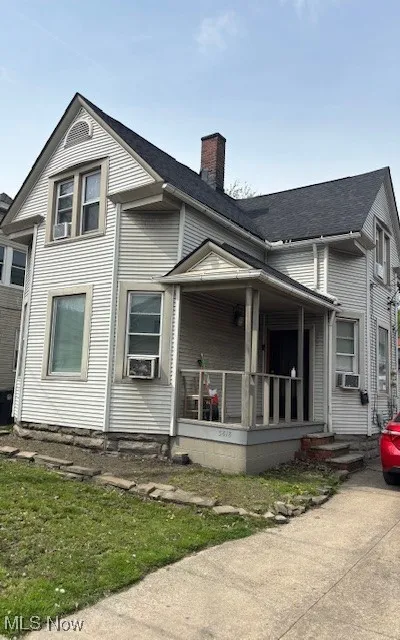 View of front of property with covered porch, cooling unit, and a chimney