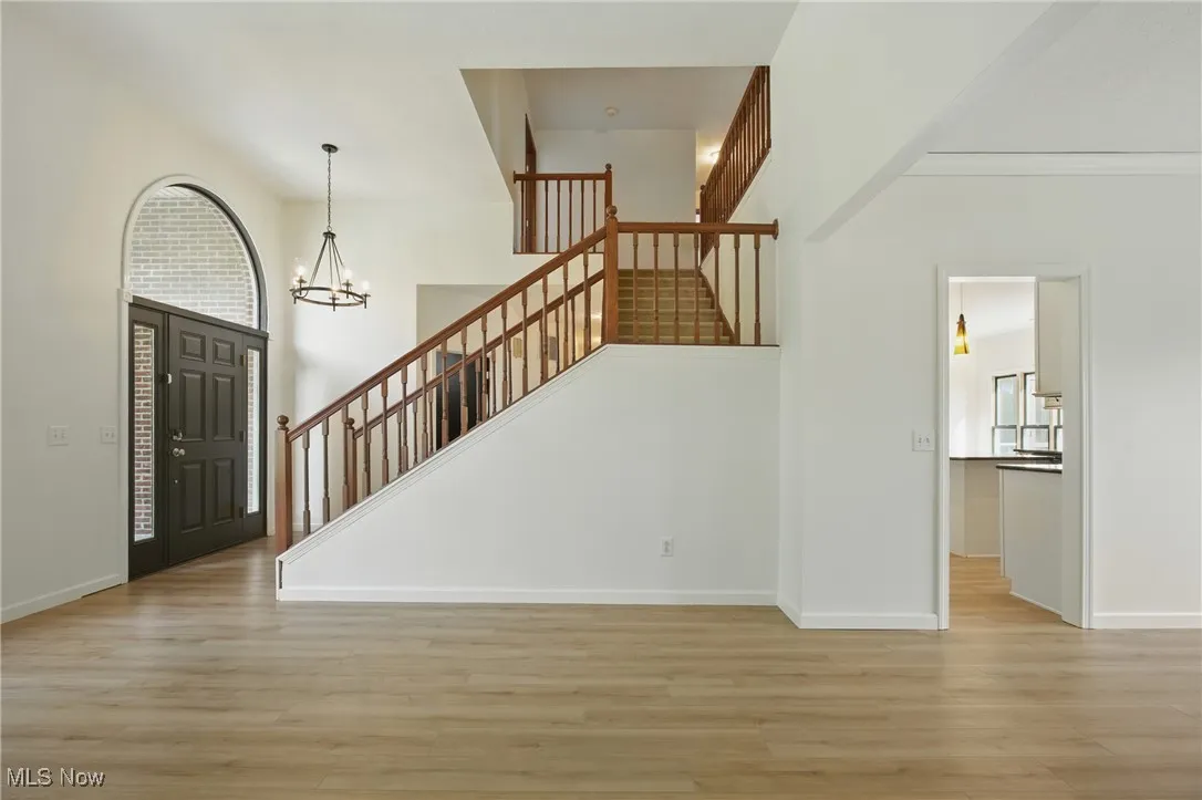 Foyer entrance featuring light wood finished floors, stairway, and a chandelier
