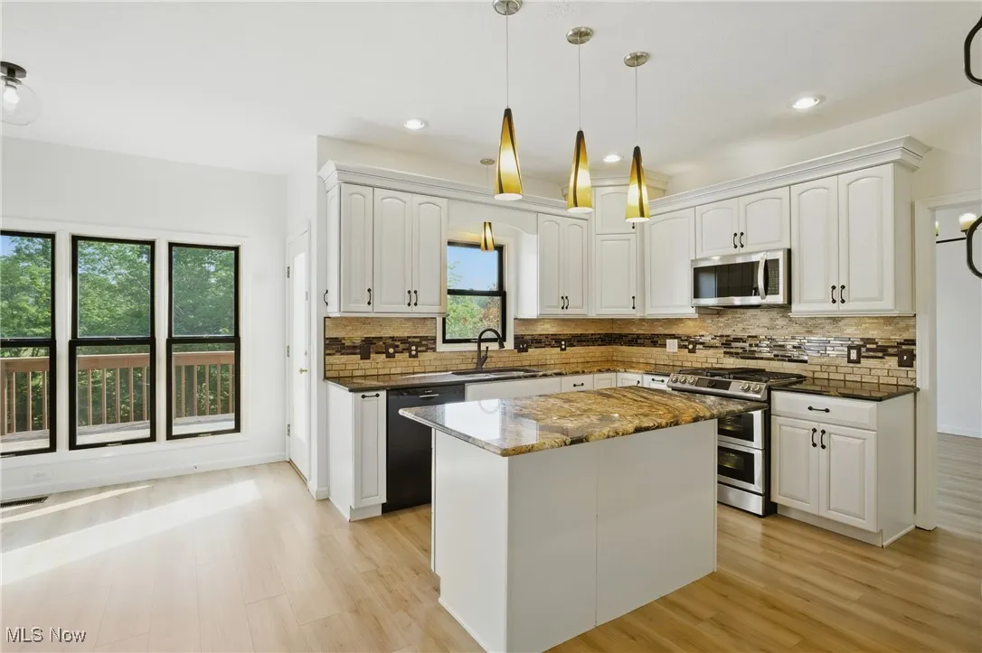 Kitchen featuring appliances with stainless steel finishes, light wood-style flooring, white cabinets, decorative backsplash, and recessed lighting