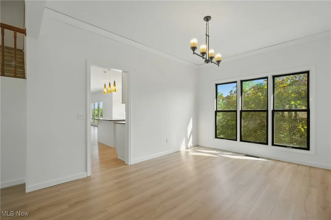 Spare room featuring a chandelier, ornamental molding, and light wood finished floors