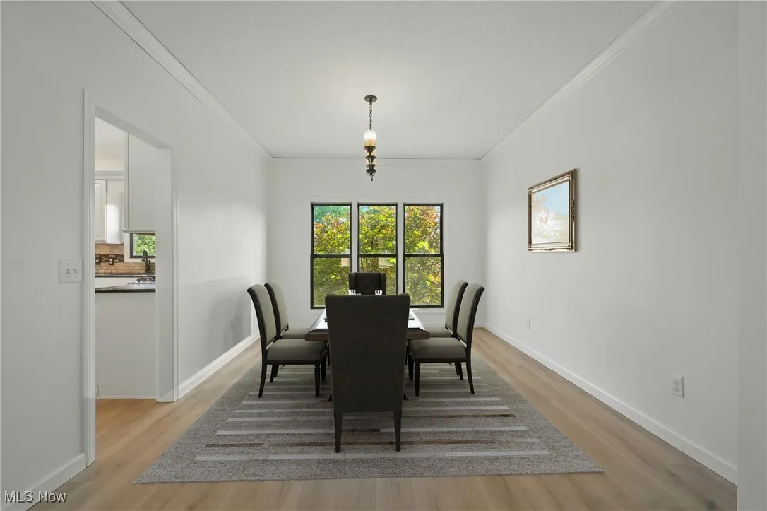 Dining space with ornamental molding and light wood finished floors