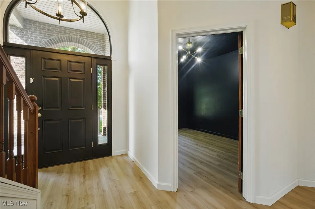 Entrance foyer with light wood-type flooring, stairway, and a chandelier