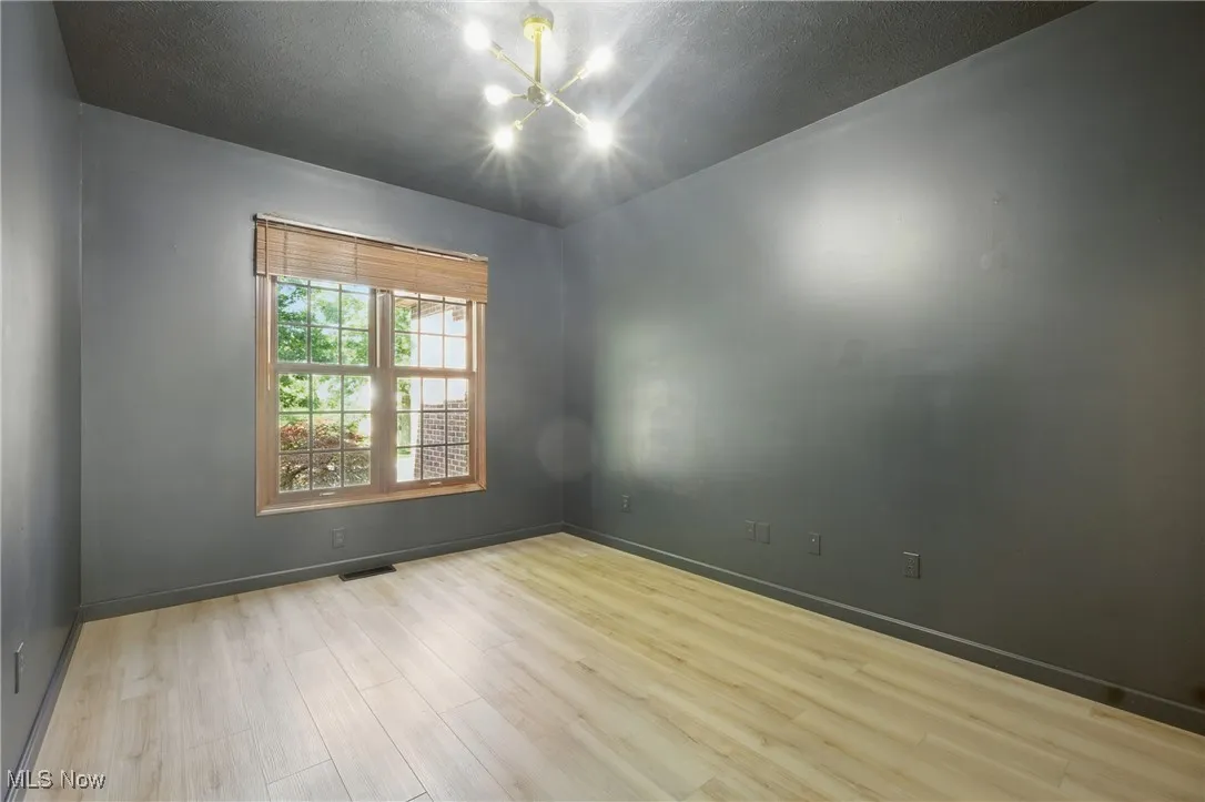 Unfurnished room with a chandelier and wood finished floors