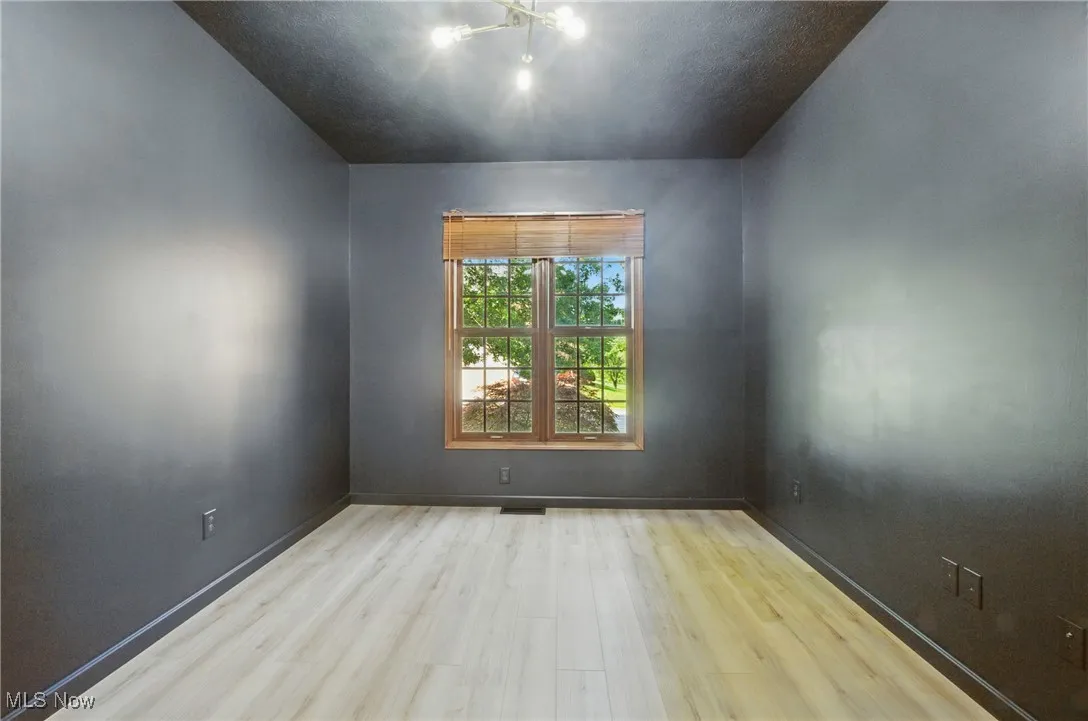 Spare room featuring wood finished floors and a chandelier