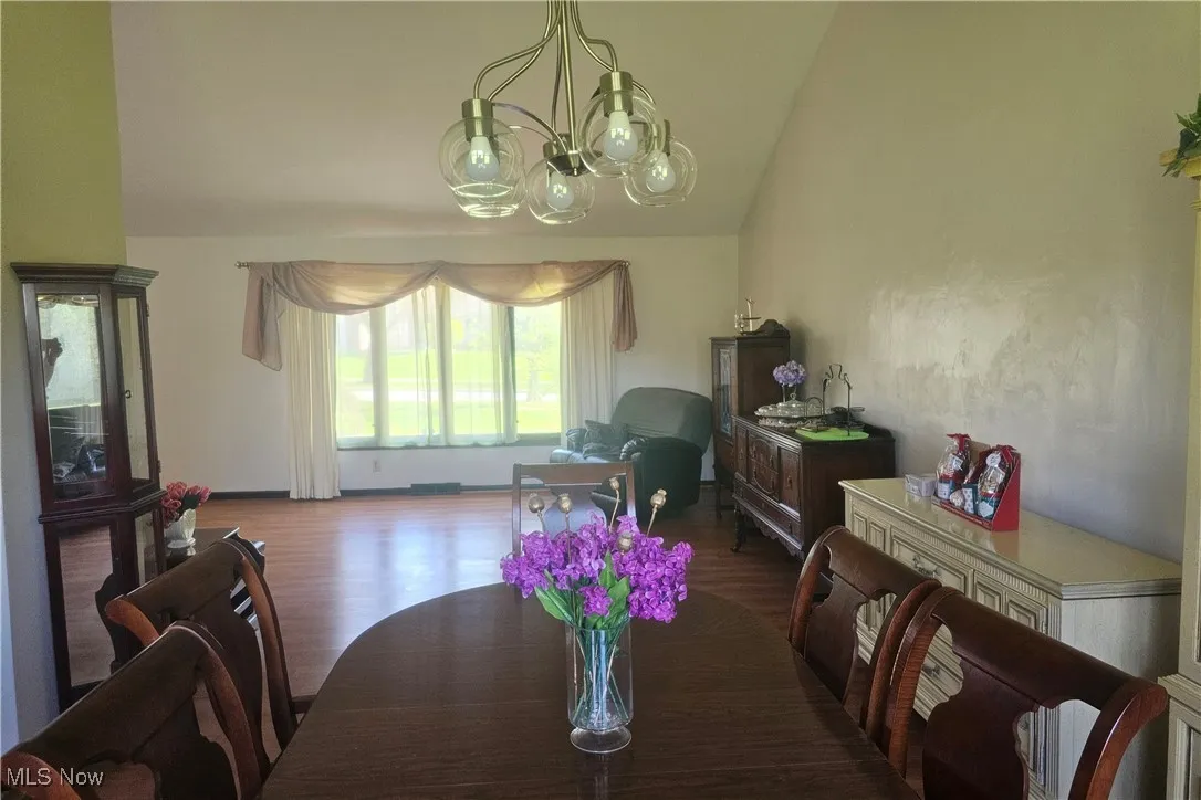 Dining space featuring a notable chandelier, wood finished floors, and lofted ceiling
